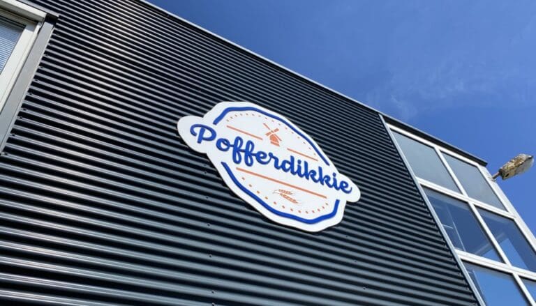 Bedrijfsnaam Pofferdikkie in witte en blauwe letters op zwarte gevel reclamebord