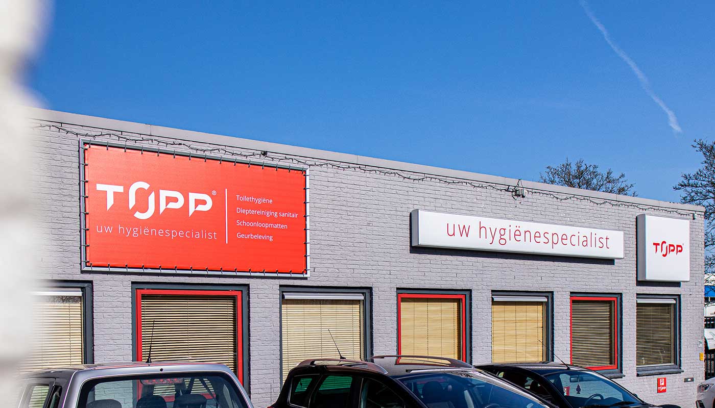 Bedrijfsgevel met rood en wit spandoek in frame met het logo en tekst topp