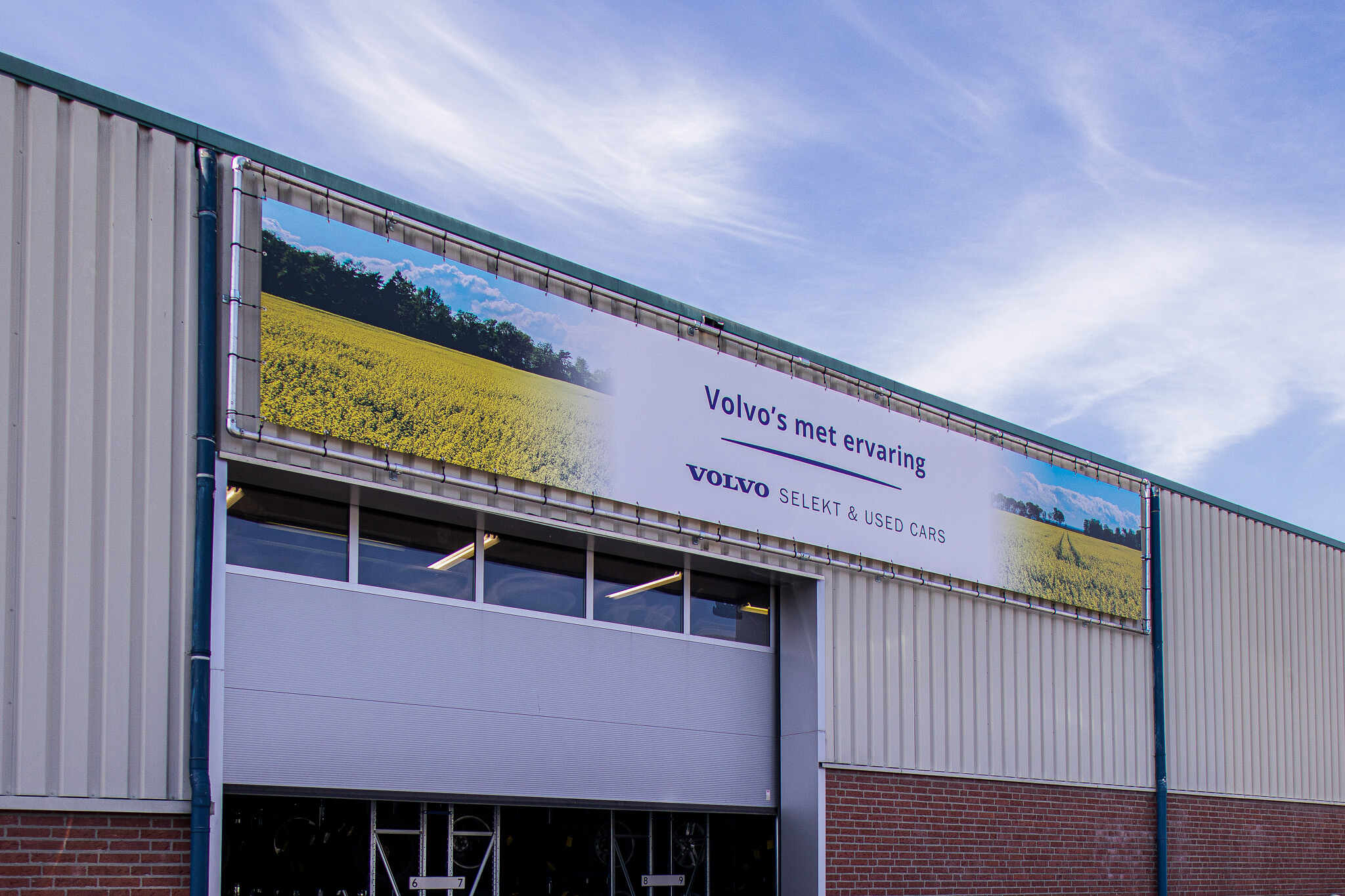 Bedrijfsgevel met groot spandoek frame en kleurrijke visuals van Venster Techniek & Ontwerp.
