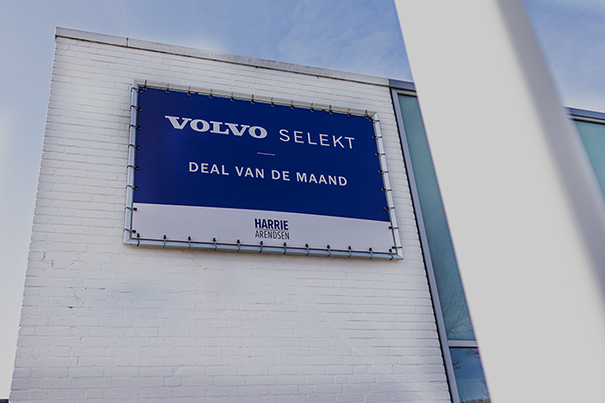 Wit gebouw met een groot spandoek in frame met de tekst "Volvo Select – Deal van de Maand.